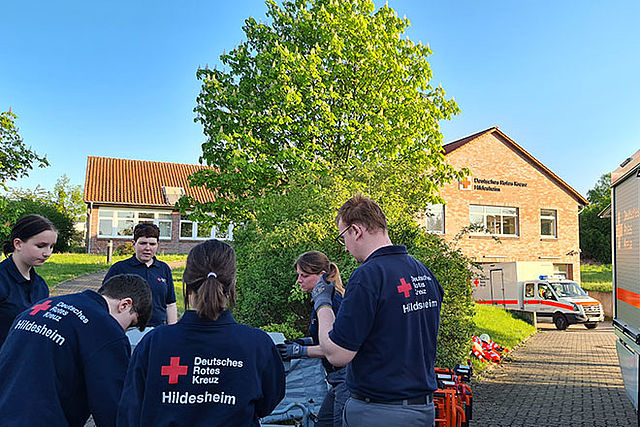 Mitglieder der Sanitätsgruppe üben auf dem Außengelände des ZfB. Sie sind in Einsatzkleidung von hinten zu sehen.