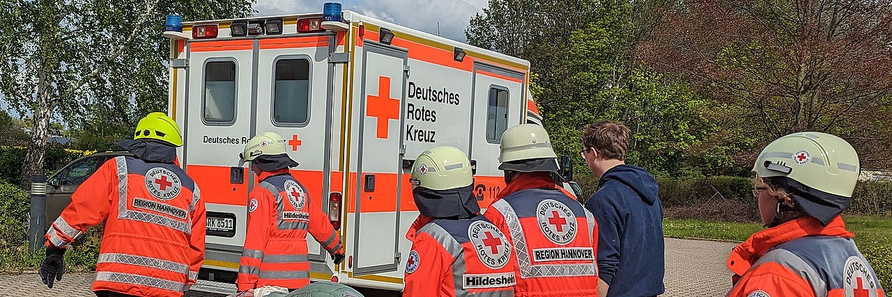 Mehrere DRK-Sanität tragen einen Verletztendarsteller auf einer Trage zum RTW.