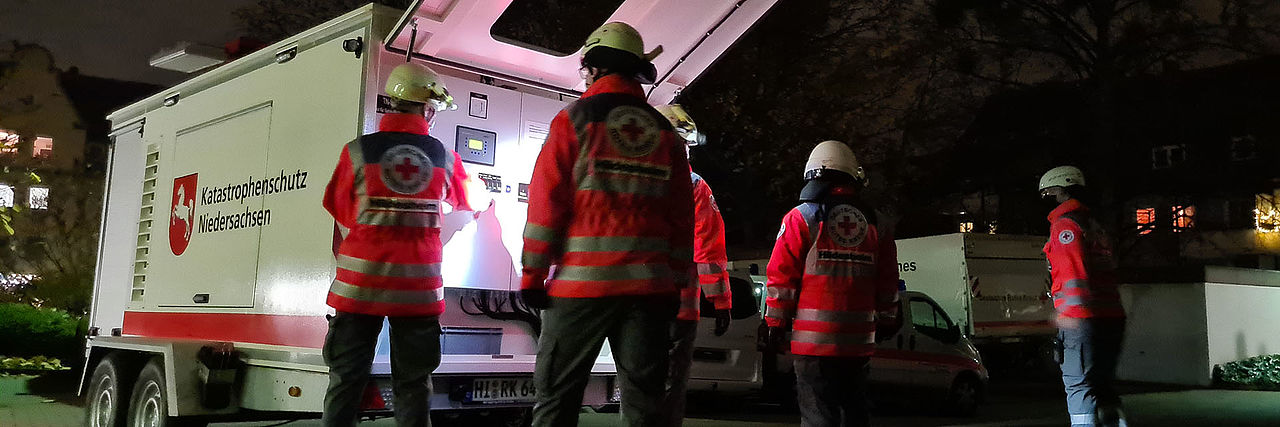 Einsatz im Dunklen bei Stromausfall. Eine Netzersatzanlage wird von Einsatzkräften in Betrieb genommen. Nur ein Teil des Bildes ist beleuchtet, was eine gespenstische Stimmung erzeugt.