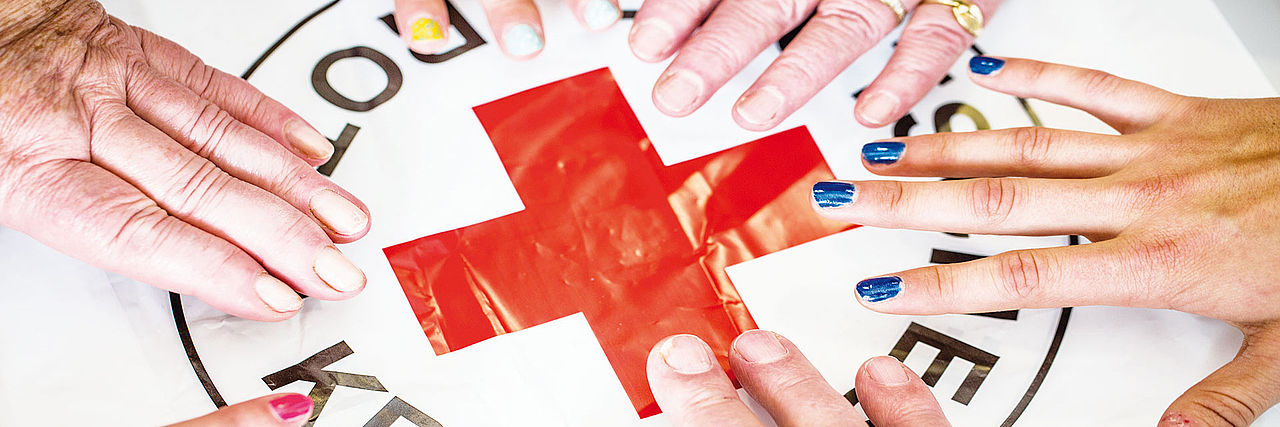 Hände auf einem Rotkreuz-Logo