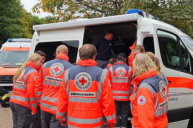 Mehrere DRK-Einsatzkräfte stehen vor dem ELW mit geöffneter Seitentür.