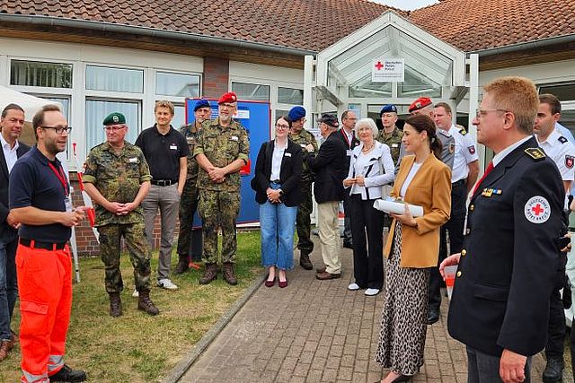 Viele Gäste der Eröffnungsfeier stehen vor dem Eingang und informieren sich.
