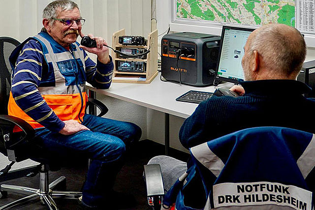 Zwei Funker sitzen an ihren Geräten. Sie haben Notfunk-Westen an.