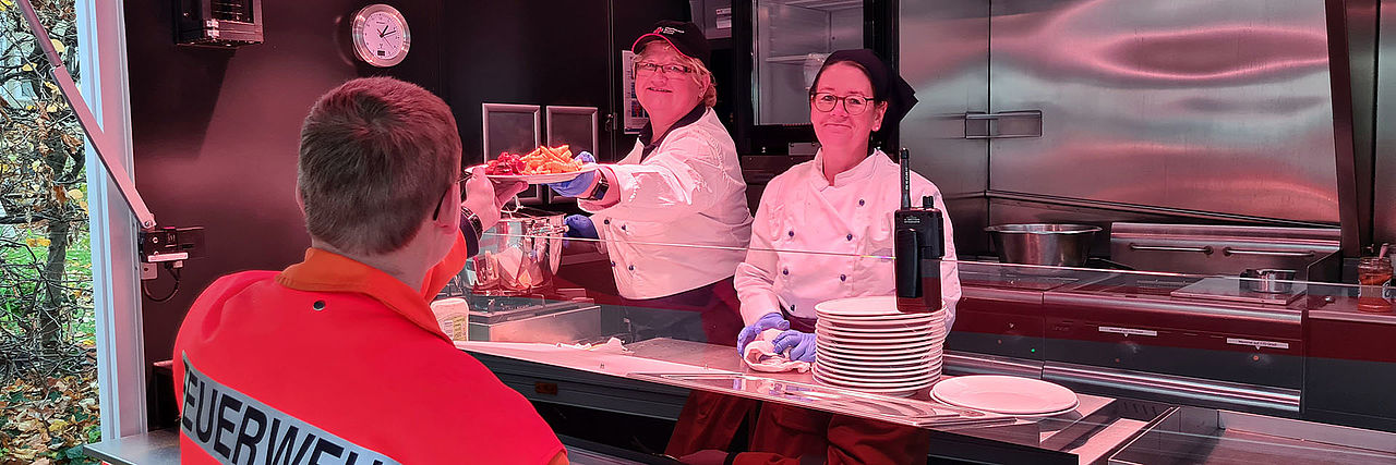 Feuerwehrmann bekommt Essen aus dem DRK-Food-Truck.