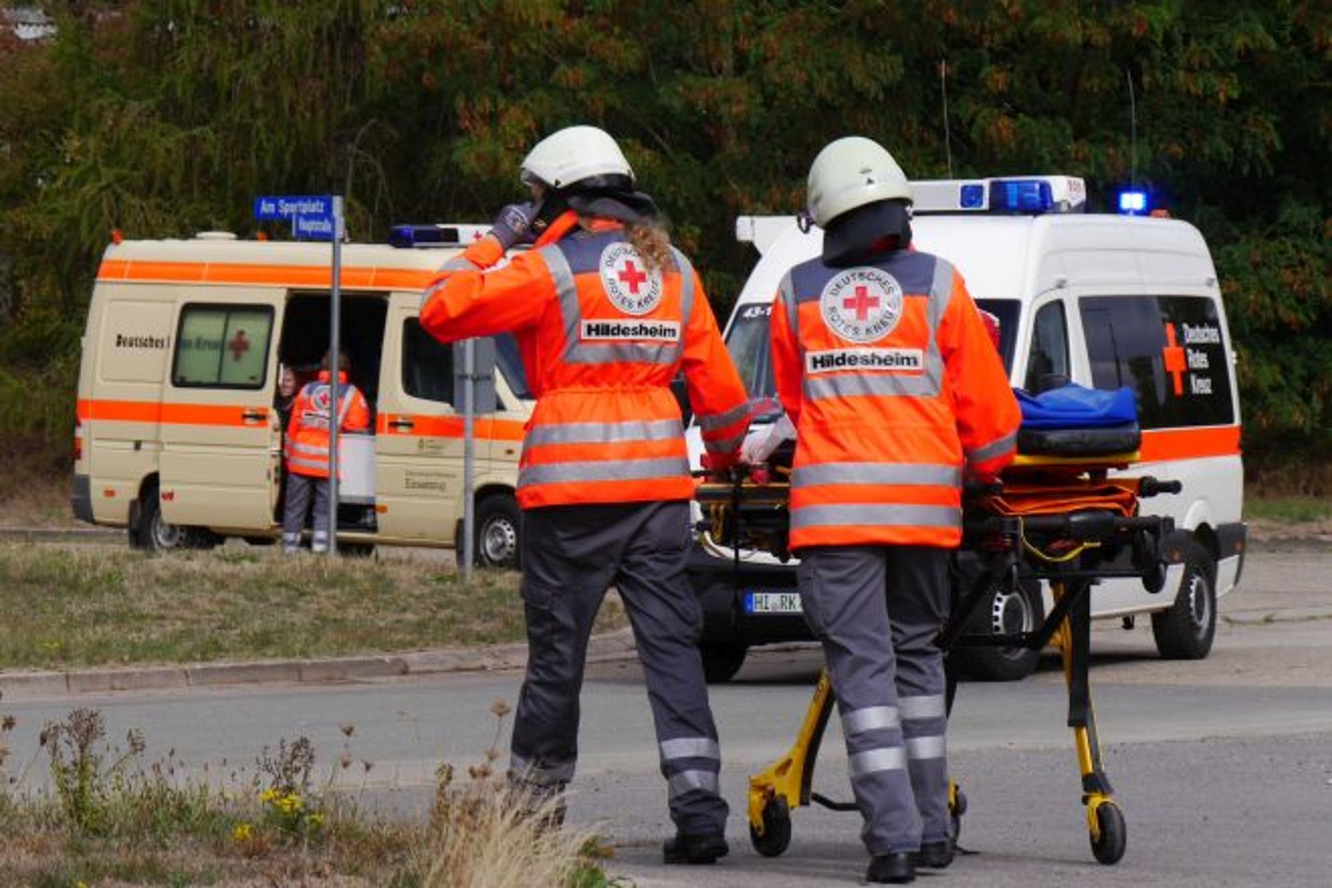 Zwei Sanitäter schieben eine Trage. Im Hintergrund Rettungsfahrzeuge.