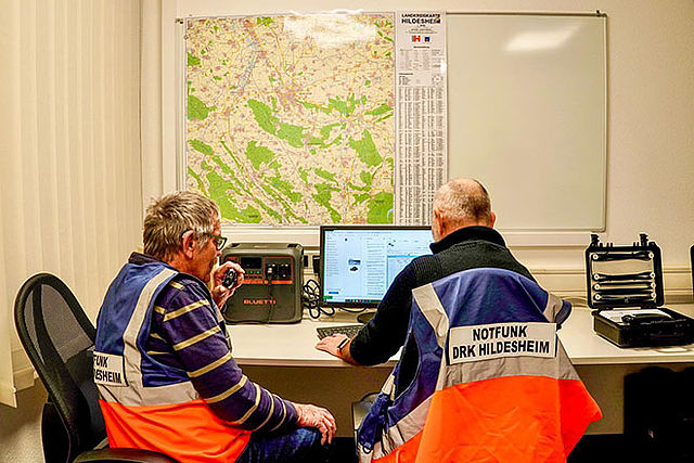 2 Funker mit Notfunk-Westen am Funkgerät und PC.