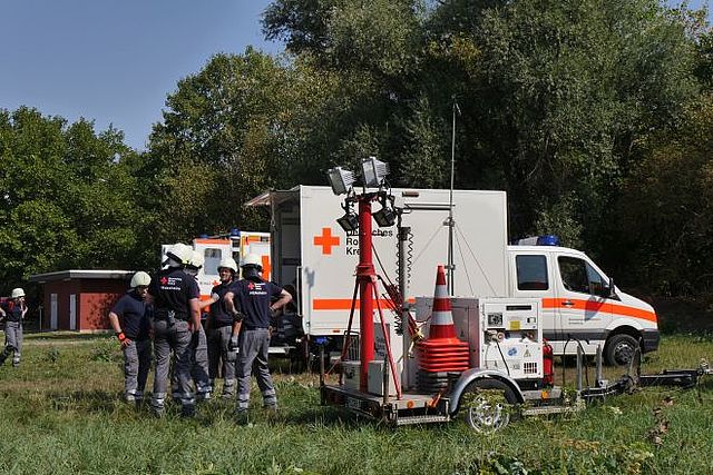 Einsatzkräfte mit Notstromaggregat aus Wiese.