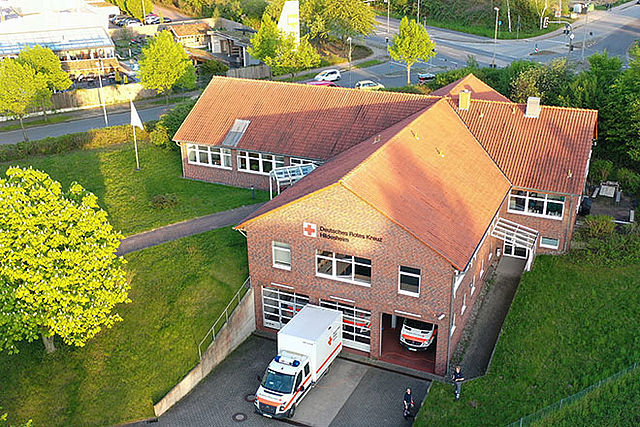 DRK-Gebäude aus der Luft fotografiert. Im Vordergrund steht ein Einsatzfahrzeug.