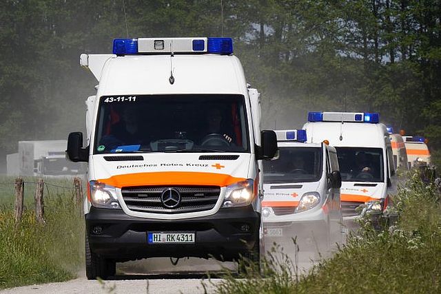 Einsatzfahrzuge fahren auf einem staubigen Feldweg auf den Betrachter zu.
