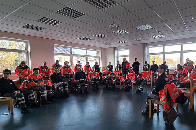 Viele Einsatzkräfte in auffälliger Einsatzbekleidung im Schulungsraum im ZfB.